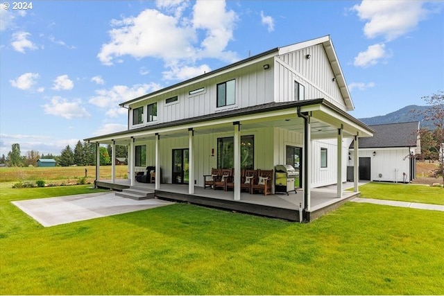 back of property featuring a patio area, a mountain view, and a yard