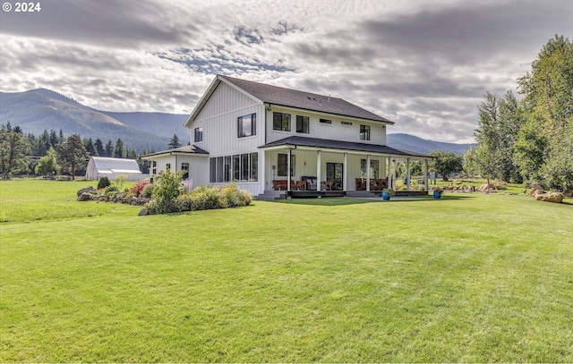 rear view of property with a mountain view, a yard, and covered porch