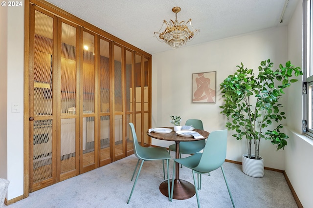 carpeted dining area featuring a notable chandelier and a textured ceiling