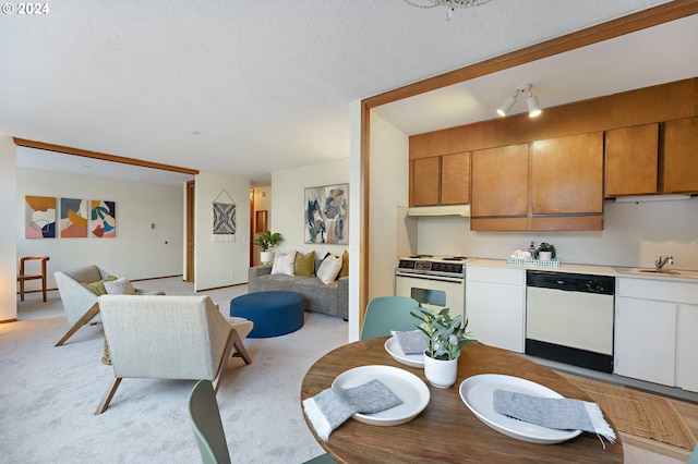 kitchen with sink, light carpet, a textured ceiling, and white appliances