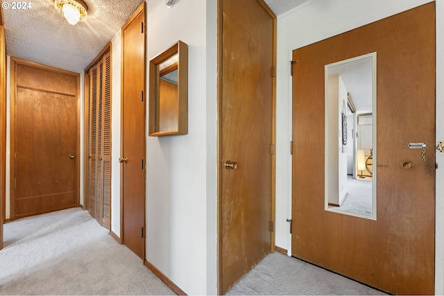 corridor featuring light carpet and a textured ceiling