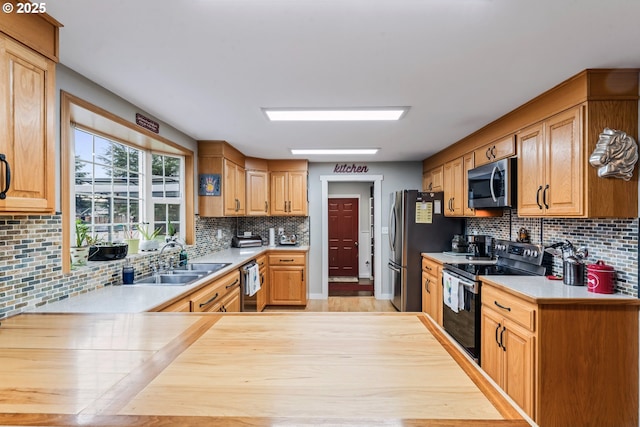 kitchen with sink, kitchen peninsula, appliances with stainless steel finishes, and decorative backsplash