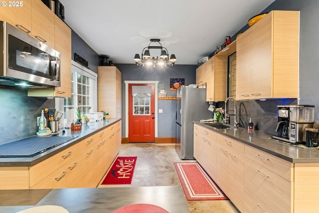 kitchen featuring light brown cabinets, stainless steel appliances, decorative backsplash, sink, and a notable chandelier