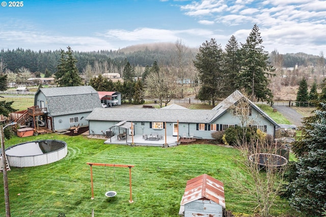 back of property with a swimming pool side deck and a lawn