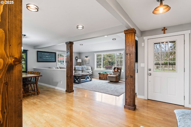 foyer entrance featuring decorative columns and light wood-type flooring