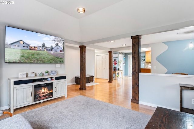 living room featuring a fireplace, decorative columns, and light hardwood / wood-style floors