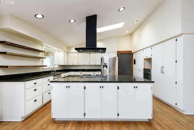 kitchen featuring a center island, lofted ceiling with skylight, white cabinets, appliances with stainless steel finishes, and island range hood