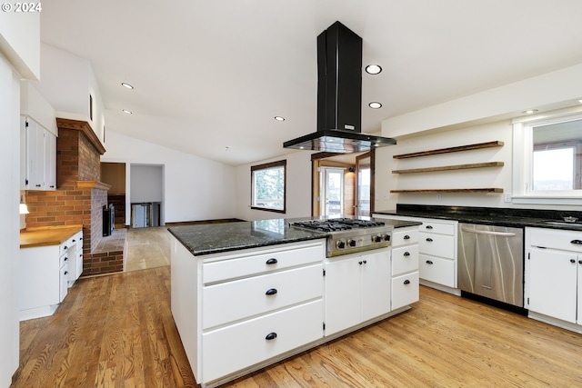 kitchen with white cabinetry, vaulted ceiling, island range hood, appliances with stainless steel finishes, and light wood-type flooring