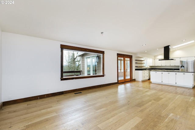 unfurnished living room with light wood-type flooring, lofted ceiling, and sink