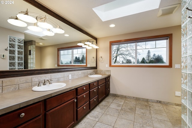 bathroom with decorative backsplash, vanity, a skylight, and tile patterned flooring