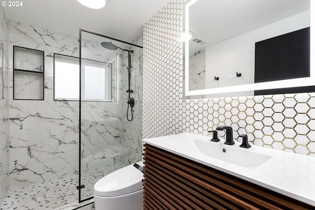 bathroom featuring backsplash, a tile shower, vanity, tile walls, and toilet