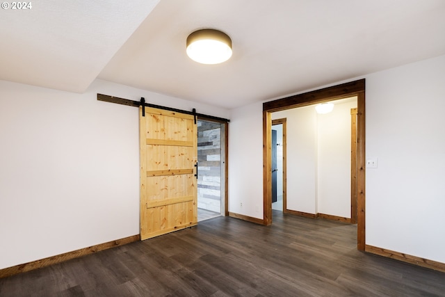 spare room with a barn door and dark hardwood / wood-style flooring