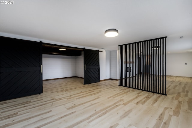 interior space featuring light wood-type flooring, a barn door, and wood walls