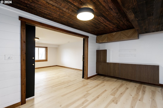 empty room featuring wood walls, light wood-type flooring, and wooden ceiling