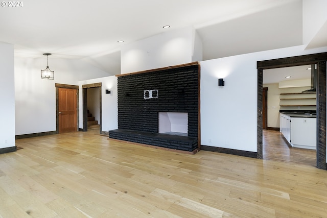 unfurnished living room with light wood-type flooring, a fireplace, and vaulted ceiling