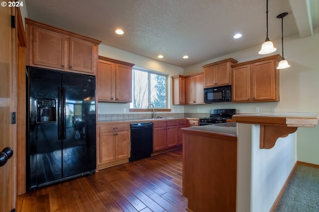 kitchen featuring dark hardwood / wood-style floors, pendant lighting, a textured ceiling, a breakfast bar, and black appliances