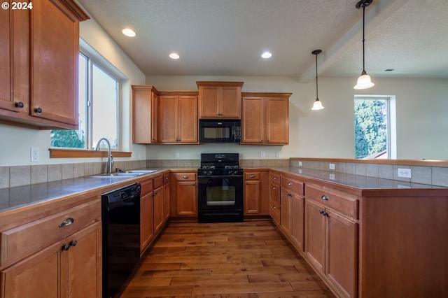 kitchen featuring a healthy amount of sunlight, hanging light fixtures, black appliances, and wood-type flooring