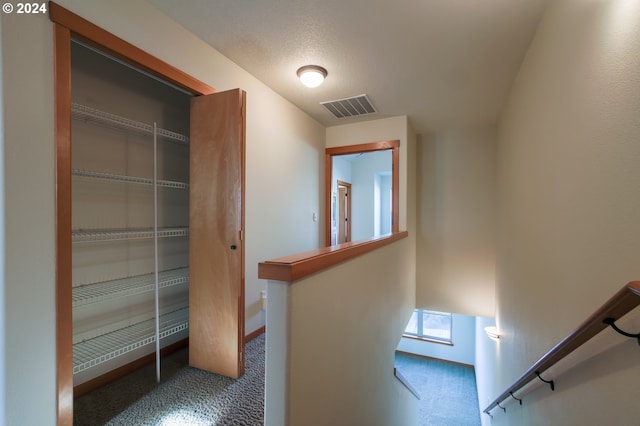 hall with dark colored carpet