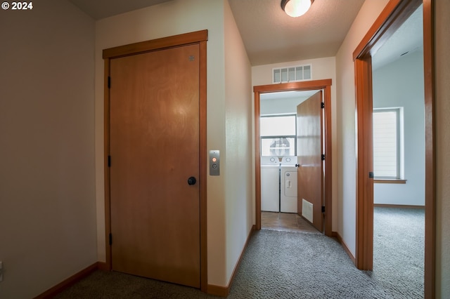 hallway featuring light carpet and separate washer and dryer