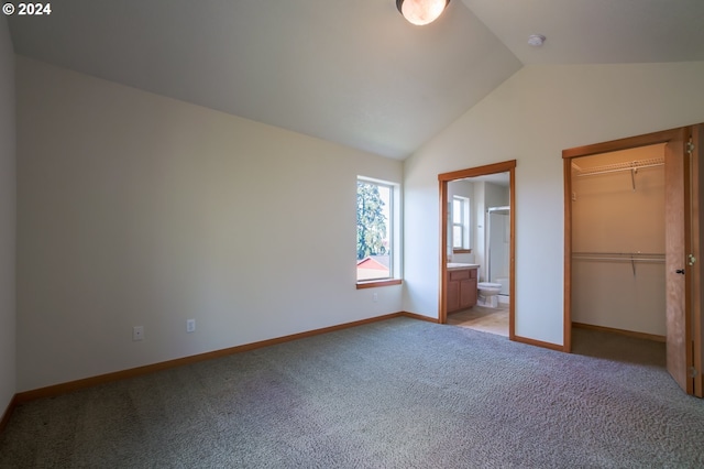 unfurnished bedroom with connected bathroom, light colored carpet, and vaulted ceiling