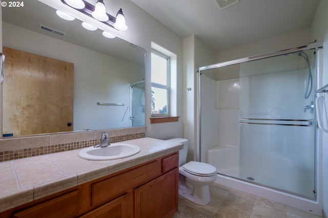 bathroom featuring vanity, toilet, and a shower with shower door