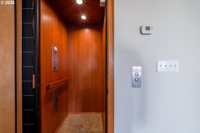 room details featuring elevator, wood walls, and carpet floors