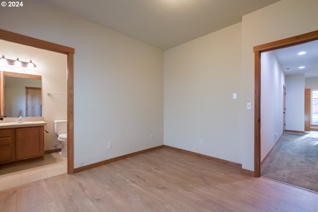 empty room with a textured ceiling, light wood-type flooring, and sink