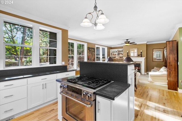 kitchen featuring light wood-type flooring, high end range, white cabinetry, pendant lighting, and crown molding