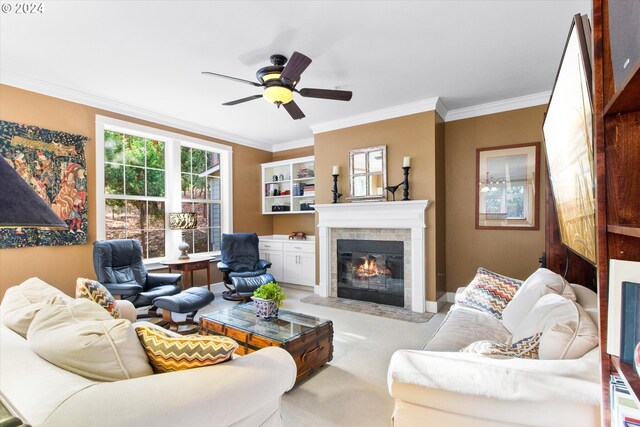 carpeted living room featuring ornamental molding, a tile fireplace, and ceiling fan