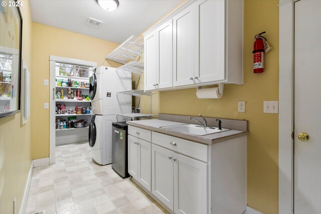 clothes washing area featuring sink, stacked washer and clothes dryer, and cabinets