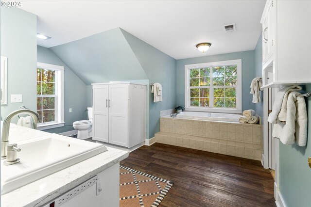 bathroom featuring a tub to relax in, wood-type flooring, a wealth of natural light, and toilet