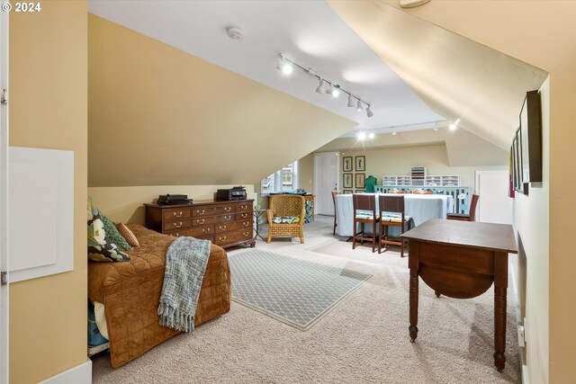 interior space featuring vaulted ceiling, carpet floors, and rail lighting