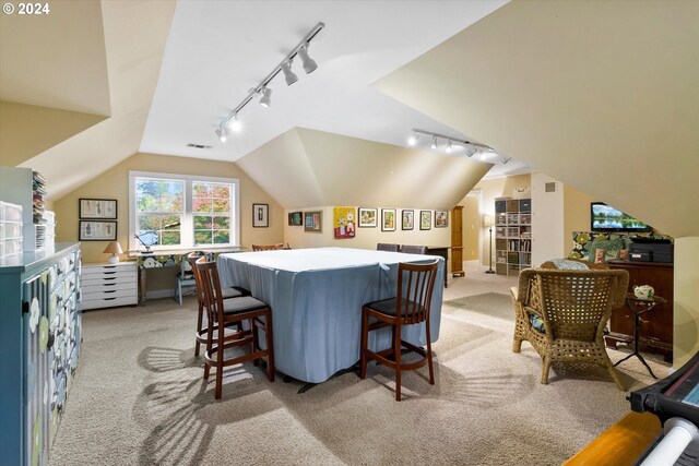 carpeted dining space featuring lofted ceiling and rail lighting