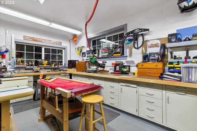 kitchen with a breakfast bar, white cabinetry, concrete flooring, and butcher block counters