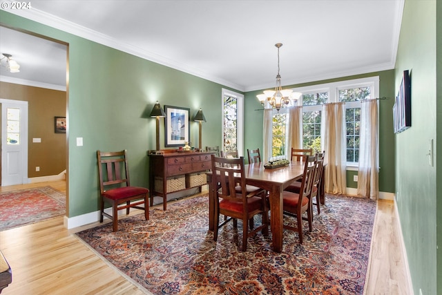 dining room featuring an inviting chandelier, baseboards, crown molding, and wood finished floors