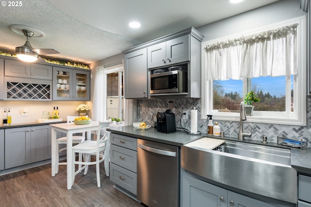 kitchen featuring appliances with stainless steel finishes, dark hardwood / wood-style floors, sink, gray cabinetry, and decorative backsplash