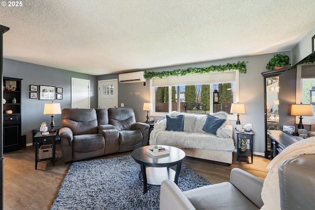 living room with hardwood / wood-style floors, an AC wall unit, and a textured ceiling