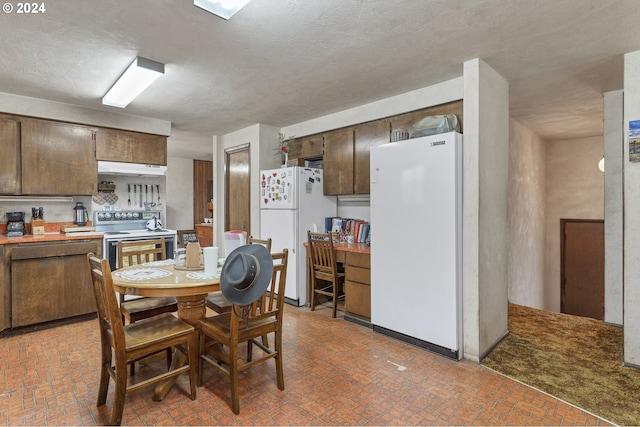 kitchen featuring a textured ceiling, white fridge, and stainless steel electric range oven