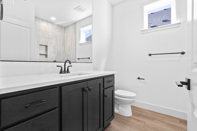 bathroom featuring visible vents, toilet, wood finished floors, baseboards, and vanity