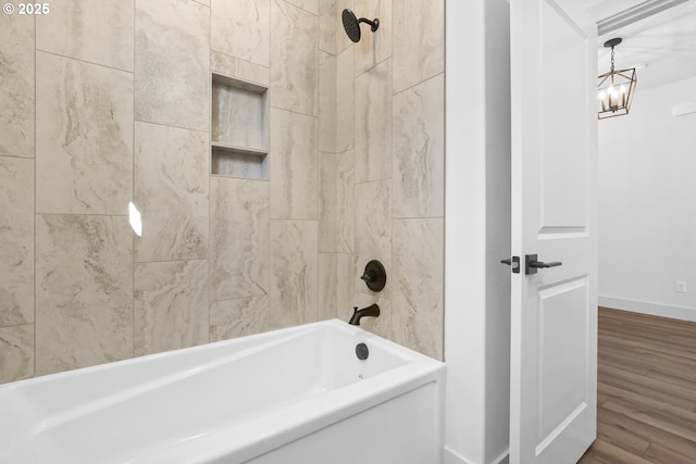 full bathroom featuring  shower combination, wood finished floors, baseboards, and a chandelier