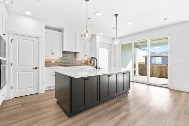 kitchen with stainless steel appliances, white cabinets, decorative backsplash, and light countertops