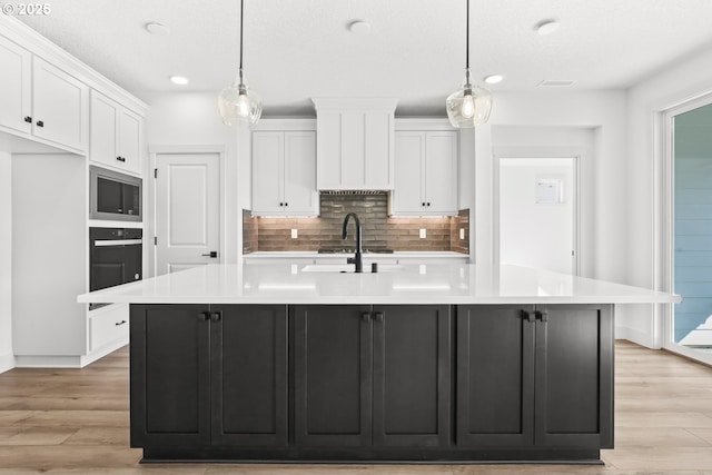 kitchen with a spacious island, light wood-style flooring, appliances with stainless steel finishes, and white cabinetry