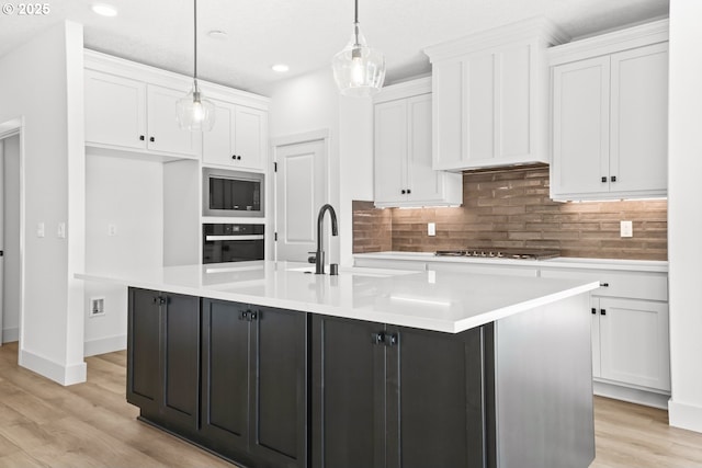 kitchen featuring stainless steel microwave, black oven, cooktop, white cabinets, and a sink