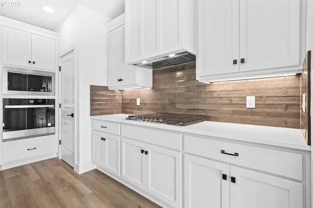 kitchen with light countertops, white cabinets, extractor fan, and stainless steel appliances