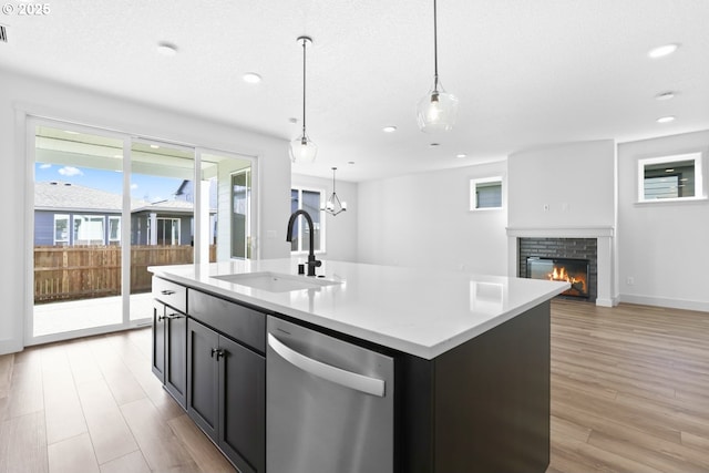 kitchen with a glass covered fireplace, a sink, light countertops, light wood-style floors, and dishwasher