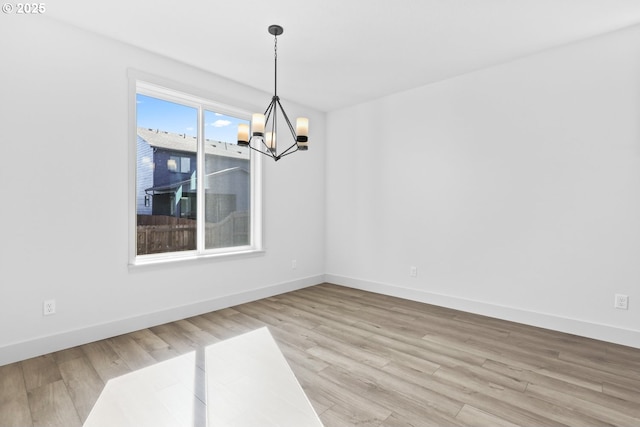 unfurnished dining area featuring light wood-style floors, baseboards, and a chandelier