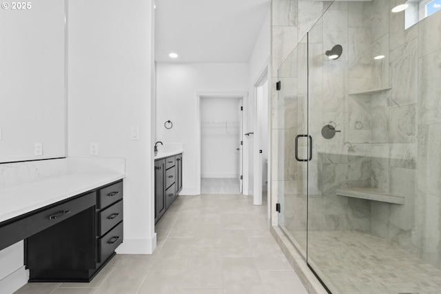 full bath with a spacious closet, baseboards, a stall shower, tile patterned floors, and vanity