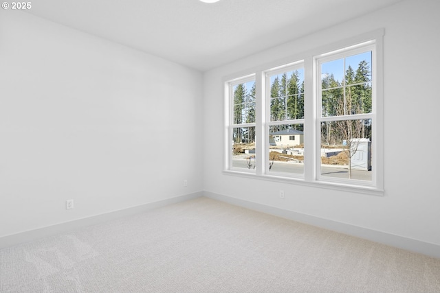 unfurnished room featuring baseboards and light colored carpet