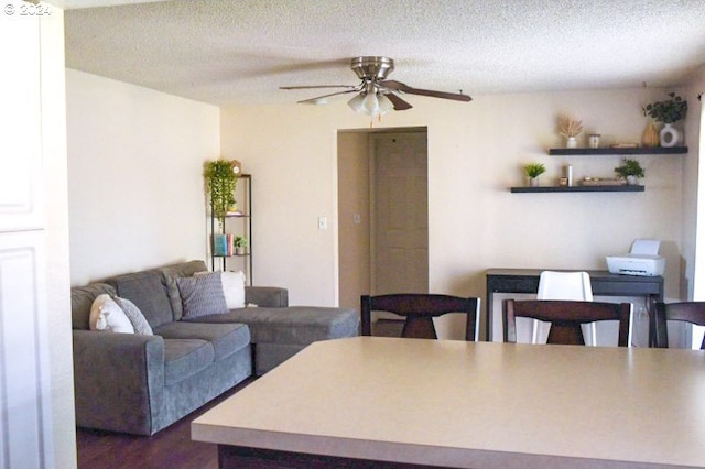 living room featuring ceiling fan, a textured ceiling, and dark hardwood / wood-style flooring