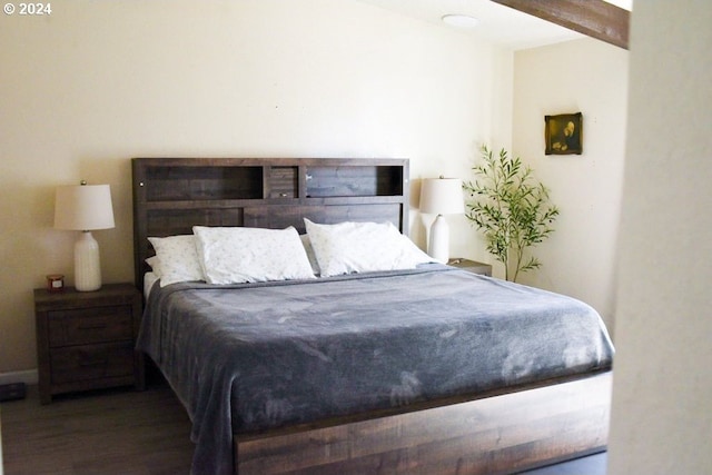 bedroom with beam ceiling and dark wood-type flooring